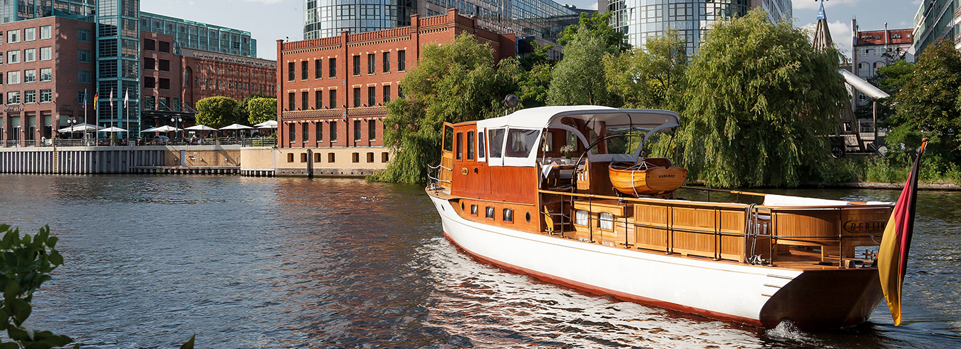 Titelbild Yacht AIDA - Foto: Yacht Aida (weiß und viel Holz) auf der Spree mit Blick auf das ABION